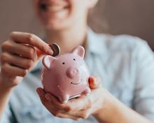 lady putting coin in pink piggy bank