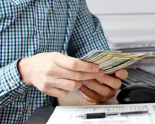 man in blue plaid shirt counting cash