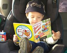 kid reading a book while wearing a Bank hat